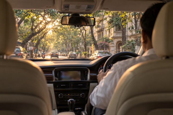 The view from the back seat of a car on a tree-lined Mumbai road in the late afternoon.