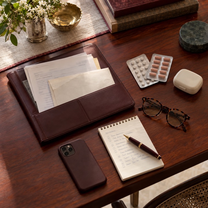 Things to bring to a first visit, laid out on a table: old reports in a leather folder, medicines and a written list, reading glasses, a phone.