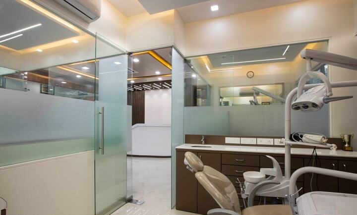 Treatment rooms behind frosted glass, a dental chair and cabinets in warm light