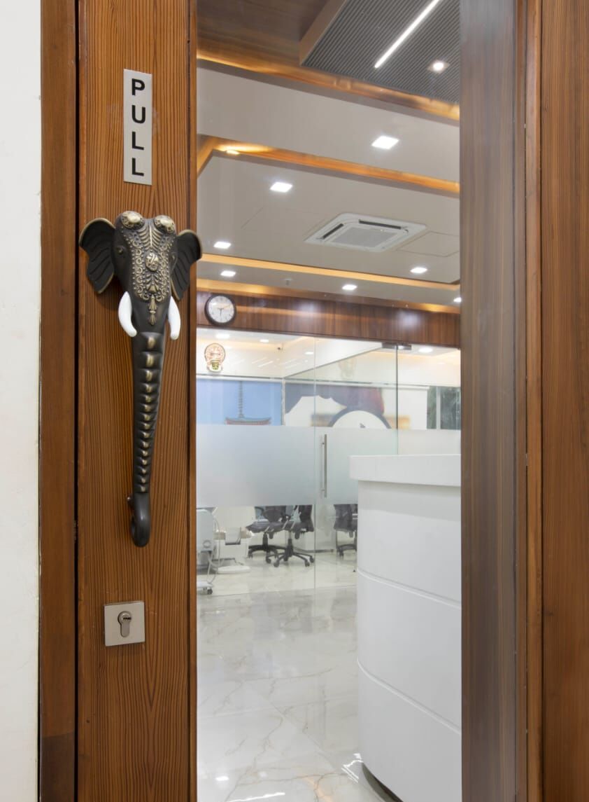 The clinic's wooden door with its black-and-brass elephant handle, the reception visible through the glass