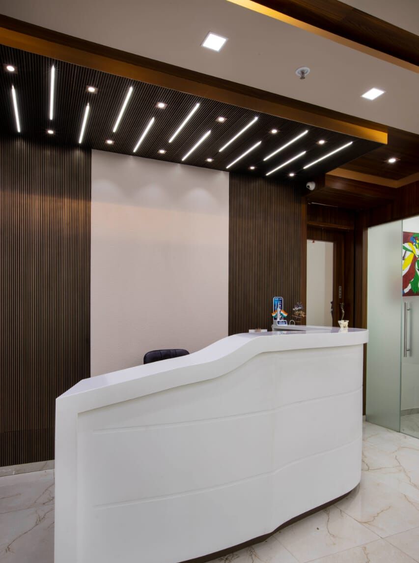 Reception: a curved white desk in front of dark wood slats, under linear ceiling lights