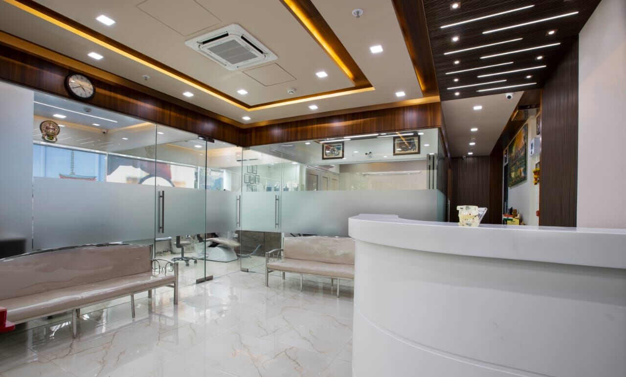 The reception on the first floor: a curved white desk, a marble floor, wood panelling and warm cove lighting